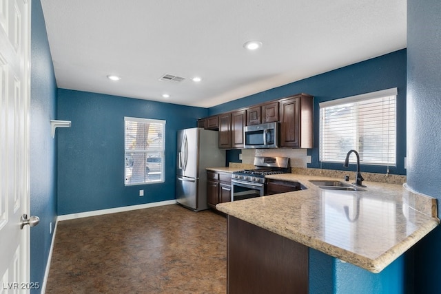 kitchen with a healthy amount of sunlight, kitchen peninsula, appliances with stainless steel finishes, and sink