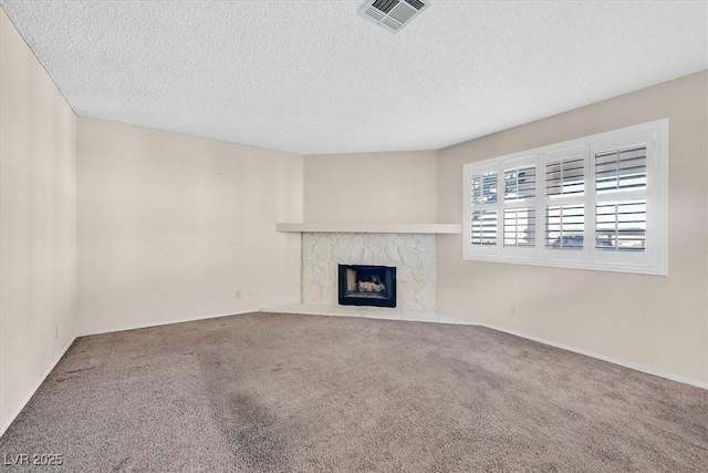 unfurnished living room featuring carpet, a textured ceiling, and a premium fireplace