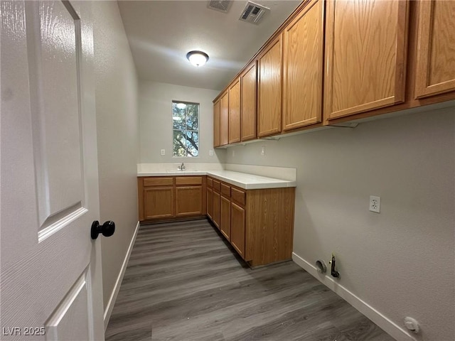 laundry room featuring dark hardwood / wood-style flooring, sink, gas dryer hookup, and cabinets