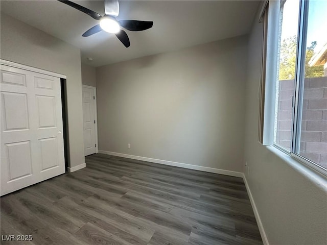 unfurnished bedroom featuring ceiling fan, multiple windows, a closet, and dark hardwood / wood-style flooring