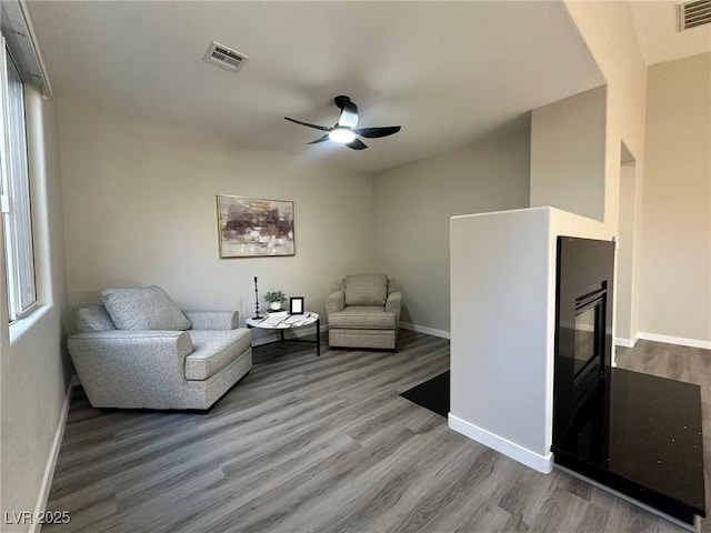 sitting room with ceiling fan and wood-type flooring