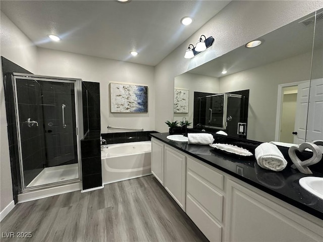 bathroom featuring plus walk in shower, hardwood / wood-style flooring, and vanity