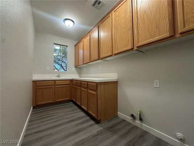 washroom with cabinets, dark hardwood / wood-style floors, gas dryer hookup, and sink