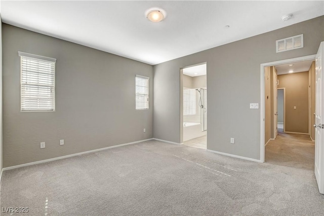 unfurnished bedroom featuring light carpet, connected bathroom, and multiple windows