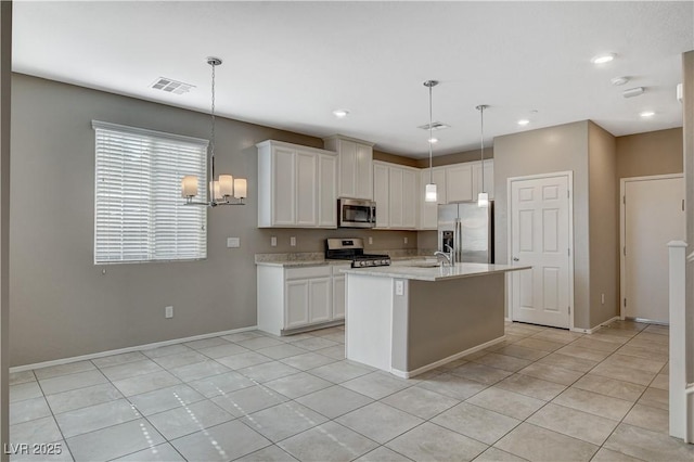 kitchen with stainless steel appliances, pendant lighting, white cabinets, and an island with sink