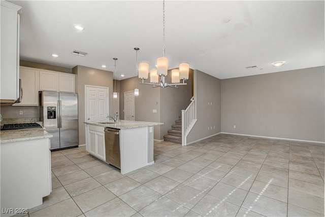 kitchen featuring pendant lighting, white cabinets, stainless steel appliances, an island with sink, and sink