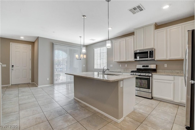 kitchen with decorative light fixtures, stainless steel appliances, an island with sink, sink, and light stone counters