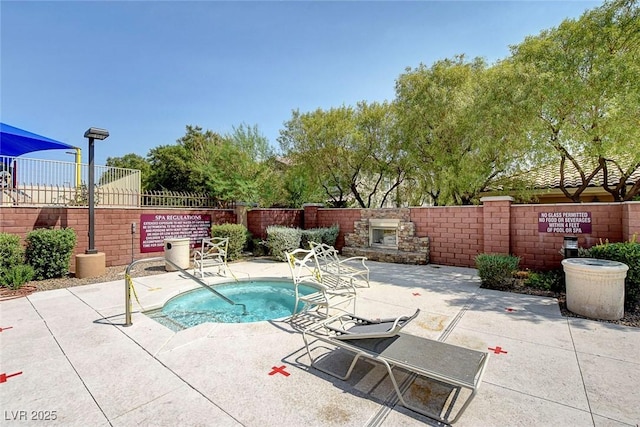 view of swimming pool featuring a hot tub, a patio, and an outdoor stone fireplace