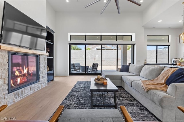 living room featuring a fireplace, light hardwood / wood-style floors, and ceiling fan