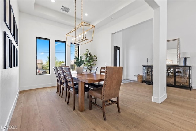 dining room with light hardwood / wood-style floors, a chandelier, and a tray ceiling