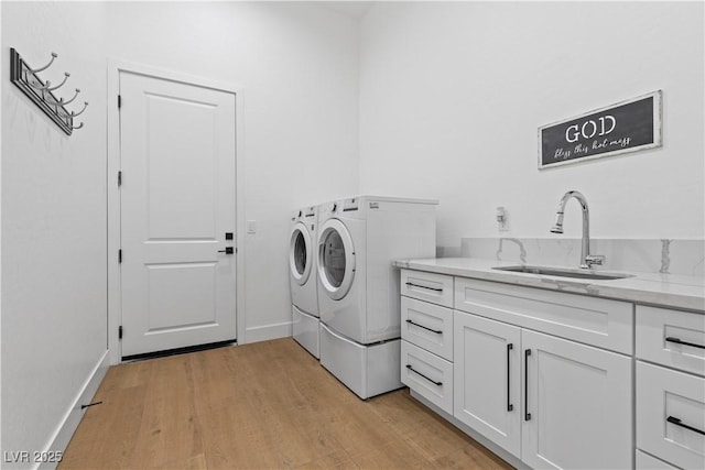 laundry area with sink, washing machine and dryer, light hardwood / wood-style floors, and cabinets