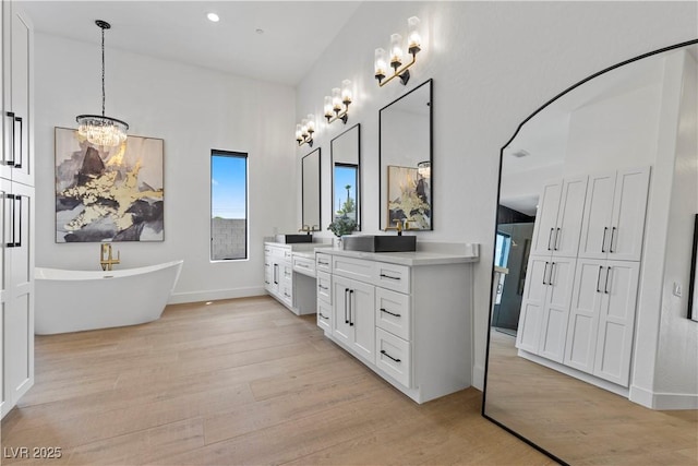 bathroom featuring wood-type flooring, a washtub, a chandelier, and vanity