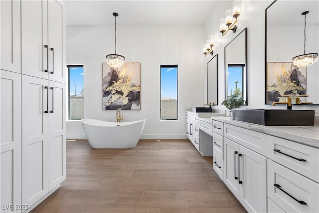 bathroom featuring hardwood / wood-style flooring, a washtub, vanity, and a notable chandelier