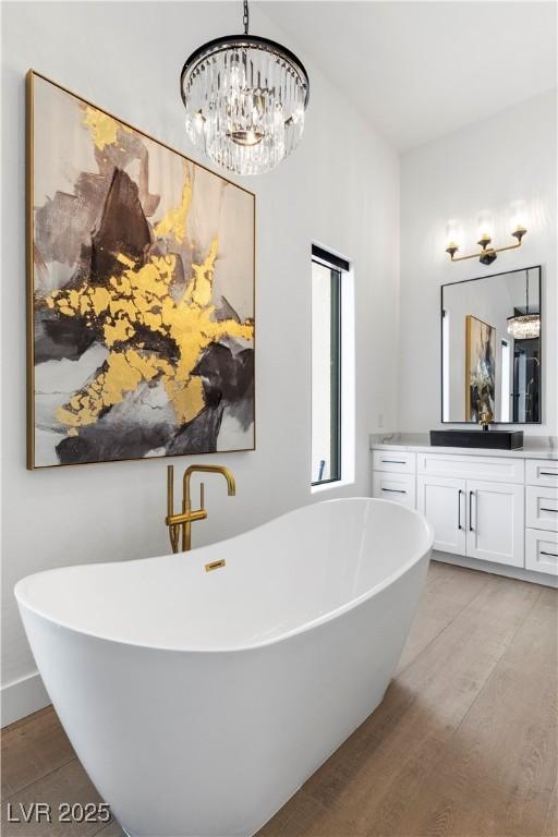 bathroom featuring vanity, a chandelier, wood-type flooring, and a bathing tub