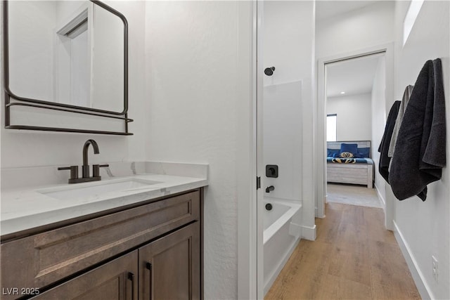 bathroom with wood-type flooring, shower / bathtub combination, and vanity