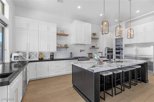 kitchen featuring decorative backsplash, a breakfast bar, white cabinetry, and a kitchen island with sink