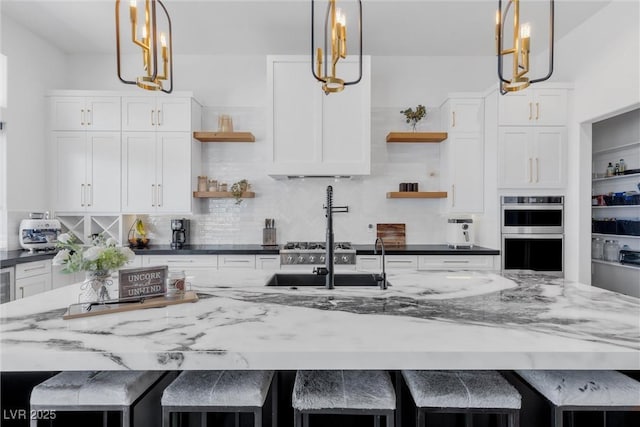 kitchen with white cabinets, pendant lighting, a large island with sink, and a kitchen breakfast bar