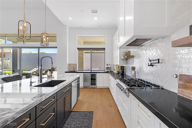 kitchen featuring hanging light fixtures, sink, white cabinetry, dark stone countertops, and stainless steel appliances