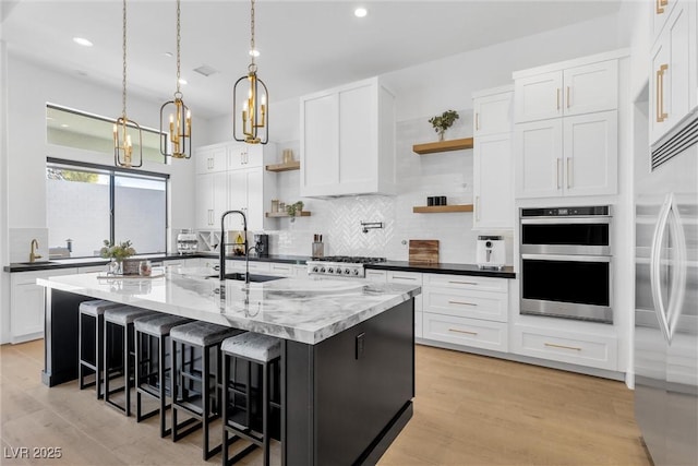 kitchen with a kitchen island with sink and white cabinetry