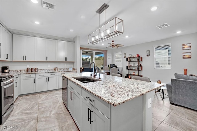 kitchen with an island with sink, ceiling fan, dishwasher, stainless steel stove, and sink