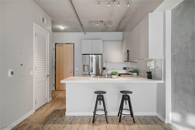 kitchen featuring white cabinetry, a breakfast bar, kitchen peninsula, and stainless steel appliances