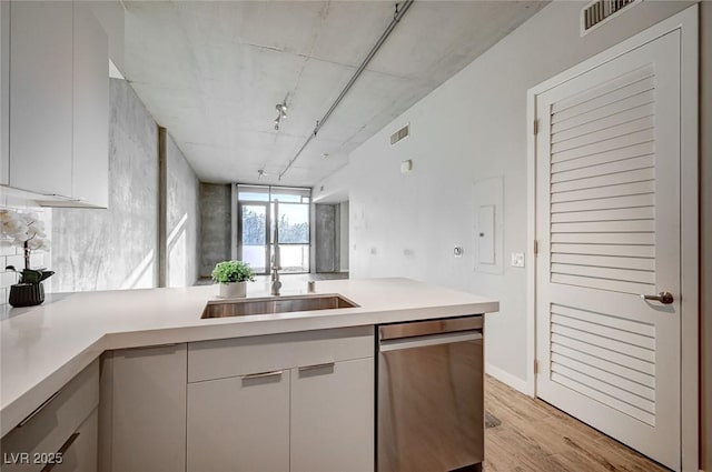 kitchen with white cabinetry, rail lighting, kitchen peninsula, light wood-type flooring, and stainless steel dishwasher