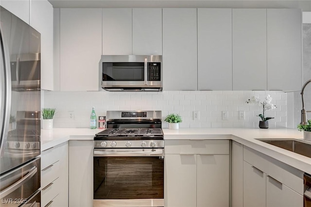 kitchen featuring appliances with stainless steel finishes, decorative backsplash, white cabinets, and sink