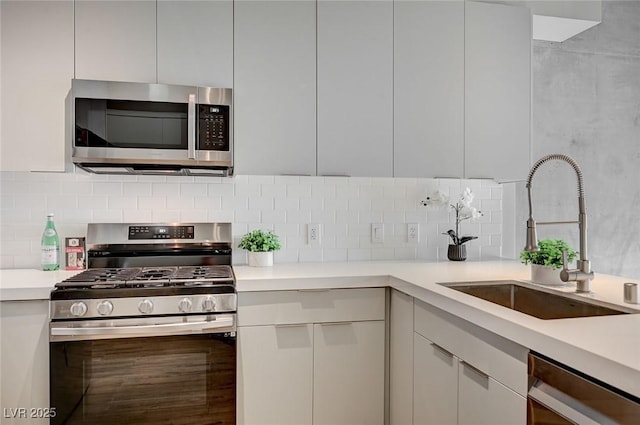 kitchen featuring appliances with stainless steel finishes, white cabinets, backsplash, and sink