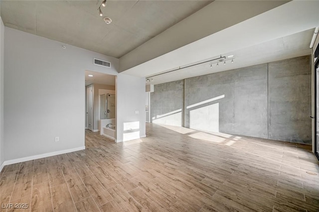 empty room with light wood-type flooring and rail lighting