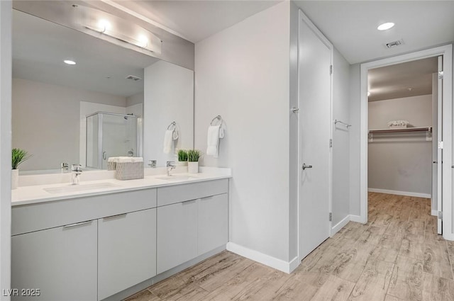 bathroom featuring a shower with shower door, vanity, and wood-type flooring