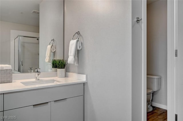 bathroom with toilet, a shower with door, hardwood / wood-style flooring, and vanity