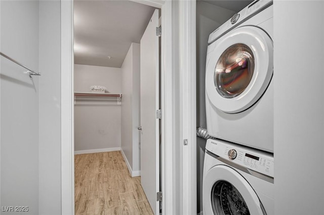 clothes washing area featuring stacked washer / drying machine and light hardwood / wood-style flooring