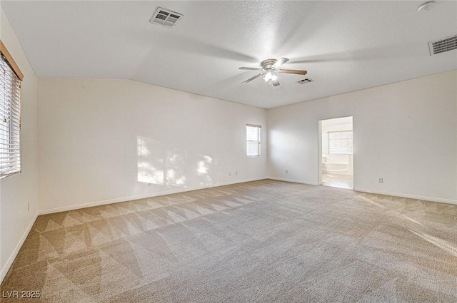 spare room with ceiling fan, light colored carpet, vaulted ceiling, and a textured ceiling