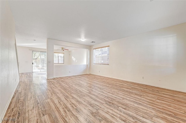 spare room featuring ceiling fan, light wood-type flooring, and a wealth of natural light