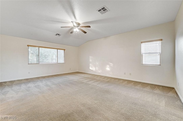 carpeted empty room featuring ceiling fan, plenty of natural light, and lofted ceiling