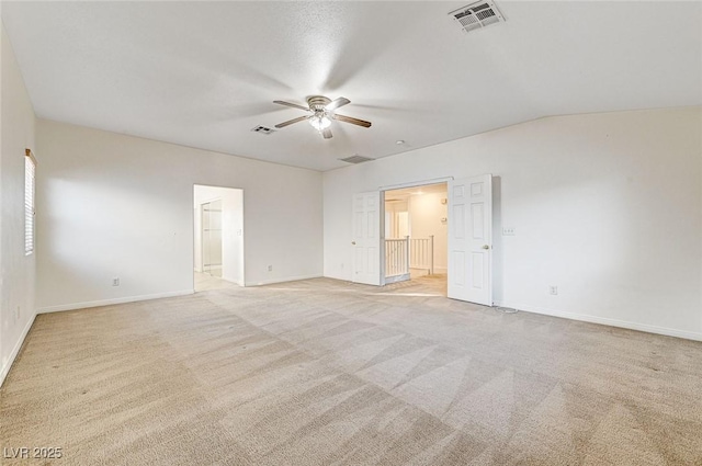 empty room with ceiling fan, light colored carpet, and vaulted ceiling