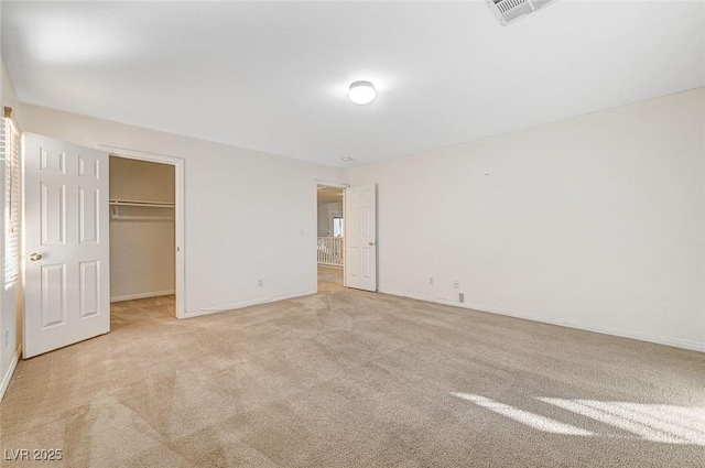 unfurnished bedroom featuring light carpet, a closet, and a walk in closet