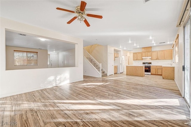 unfurnished living room featuring ceiling fan, sink, and light wood-type flooring