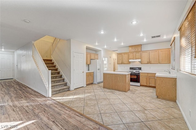 kitchen featuring light tile patterned flooring, a center island, and white appliances