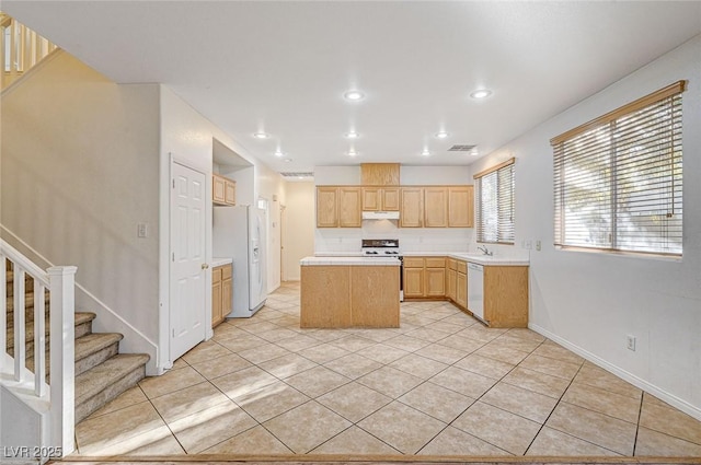 kitchen featuring light tile patterned flooring, white appliances, light brown cabinets, and a kitchen island