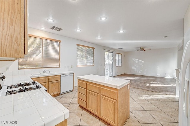 kitchen featuring ceiling fan, dishwasher, tile countertops, a center island, and light brown cabinetry