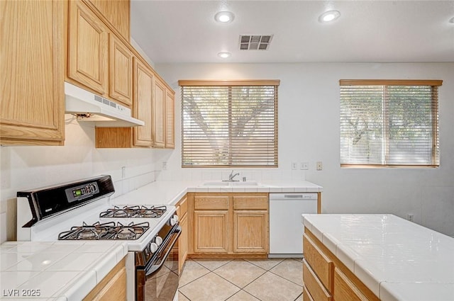 kitchen featuring tile counters, white appliances, light tile patterned flooring, light brown cabinetry, and sink