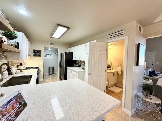 kitchen featuring white cabinetry, range with gas cooktop, kitchen peninsula, backsplash, and sink