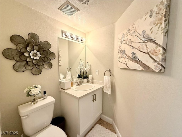 bathroom with toilet, vanity, and a textured ceiling