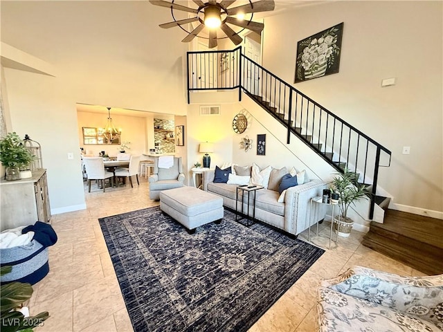 living room with light tile patterned floors, ceiling fan with notable chandelier, and a high ceiling