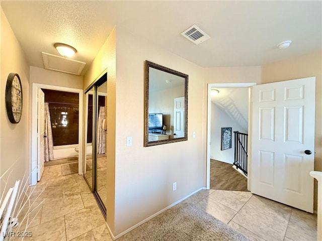 hall featuring light tile patterned floors and a textured ceiling