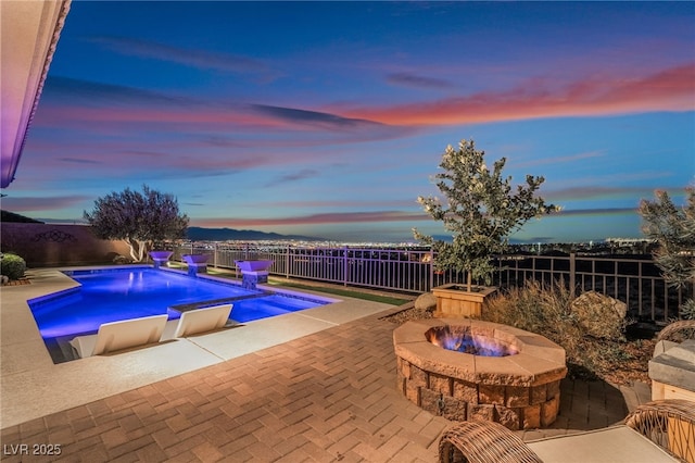 pool at dusk featuring an outdoor fire pit and a patio