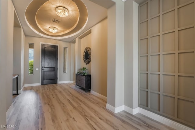 entryway with light wood-type flooring and a raised ceiling