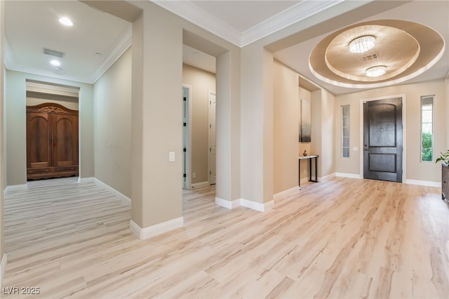 entrance foyer with a tray ceiling, crown molding, and light wood-type flooring