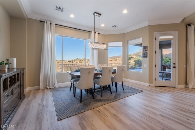 dining area featuring light wood-type flooring, ornamental molding, and an inviting chandelier